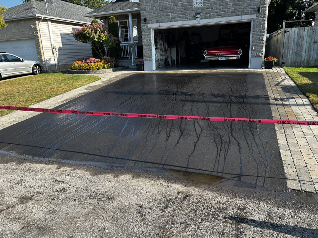 Paved driveway with open garage and car insed