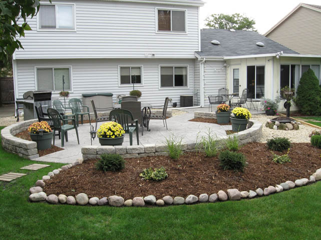 Concrete patio with garden bed around it and pathway leading to house.